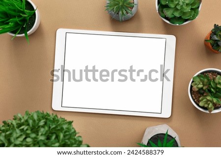 Modern tablet and houseplants on dark beige background, flat lay. Space for text