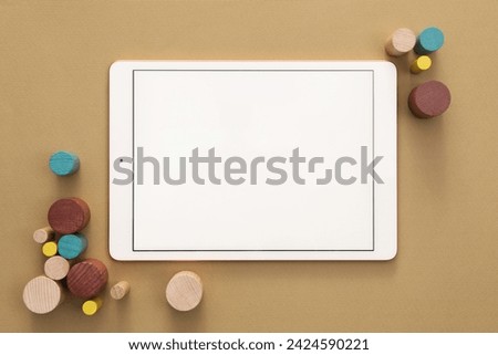 Modern tablet and wooden toys on brown background, flat lay. Space for text