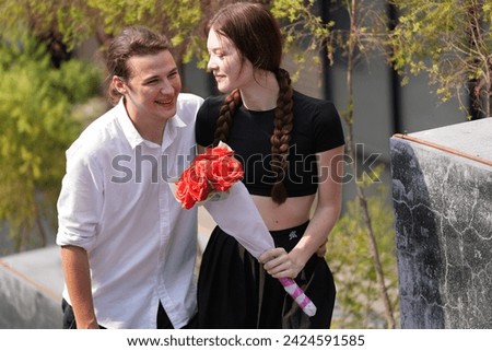 couple young man and woman hugging and holding the red bouquet rose flowers at outdoor space. Concept couple life with love and happy moment.