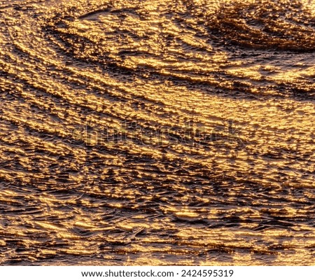 North-eastern European river after frosty winter. Ice began to melt, ice is saturated with meltwater. The morning sun colors ice surface, sunny path, iridescent reflection of sun on surface of ice Royalty-Free Stock Photo #2424595319