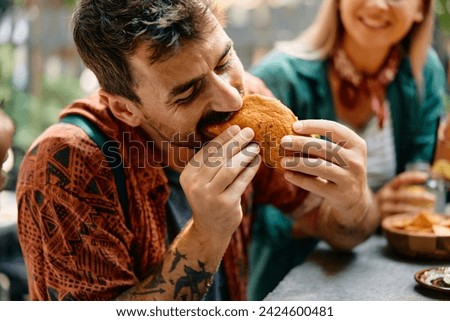 Young man biting a tacos while having lunch in restaurant.