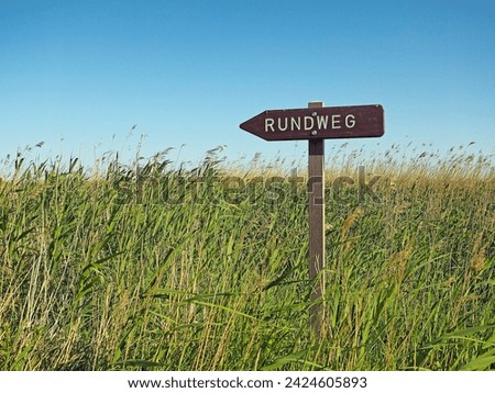 Sign pointing to a circular hiking path in the middle of a reed landscape