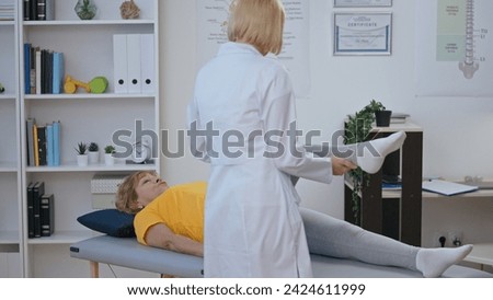 A highly qualified orthopedist checks the movability of a female patient's knee, making a diagnosis Royalty-Free Stock Photo #2424611999