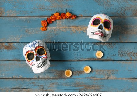 Painted skulls with marigold flowers and candles on blue wooden background. Celebration of Mexico's Day of the Dead (El Dia de Muertos)