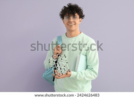 Male student with molecular model on lilac background