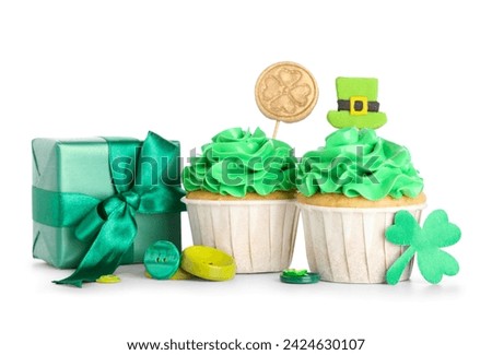Tasty green cupcakes with gift box and buttons for St. Patrick's Day on white background
