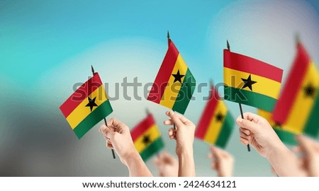 A group of people are holding small flags of Ghana in their hands.