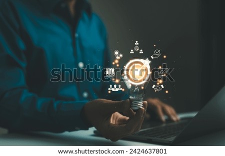 Business goals and target success concepts. Businessman holding a light bulb with business icons. business growth, Achievement company, corporate startup, investment goal, Planning ideas and strategy,