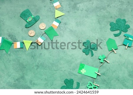 Paper garland with clover and Irish flags for St. Patrick's Day celebration on green background