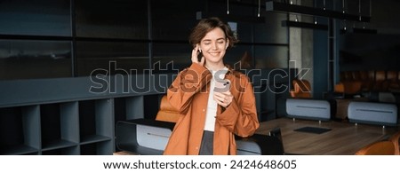Image of office worker, employee working in conference room, talks on mobile phone with wireless headphones.