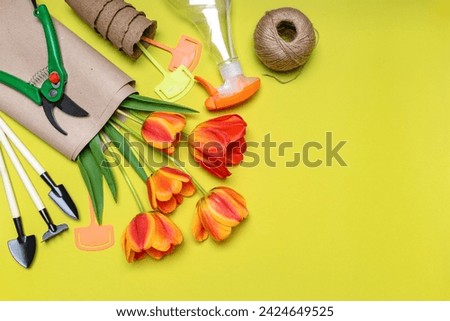 Fresh tulips flowers, seedling pots, ball of twine, garden tools and signs on light pastel background. Creative composition. Gardening, spring work concept. Flat lay, top view, copy space