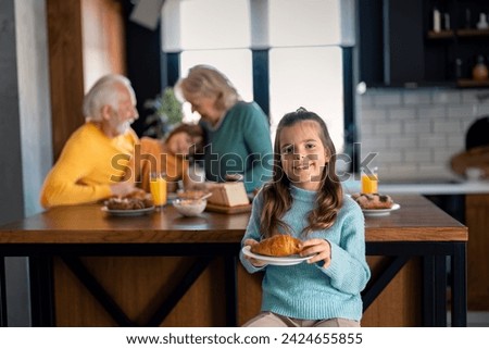 Portrait of a cute little girl with her favorite croissant.  Food and happy kids. Carefree childhood. Family time at breakfast.