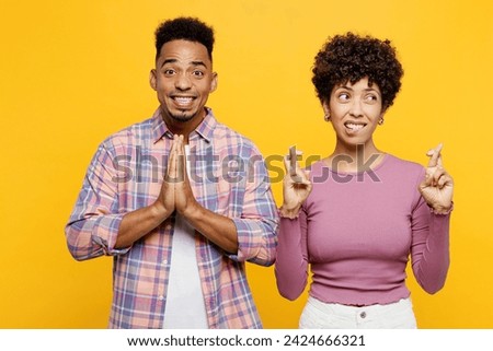 Young couple two friend family man woman of African American ethnicity wear purple casual clothes together hold hands folded in prayer gesture, keep fingers crossed isolated on plain yellow background Royalty-Free Stock Photo #2424666321