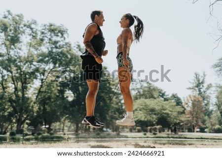 A Caucasian couple jumps rope with friends in a sunny park. They warm up and stretch before a fitness challenge. Smiling and persistent, they motivate each other in their healthy lifestyle.