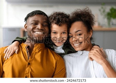Happy black family moment captured as smiling mother, father and their son share close, affectionate embrace, exuding joy and togetherness Royalty-Free Stock Photo #2424672173