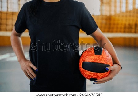 Cropped picture of a female professional volleyball player standing at indoor court with a ball in hand. An unrecognizable professional teenage sportswoman with a volleyball in hands on court.