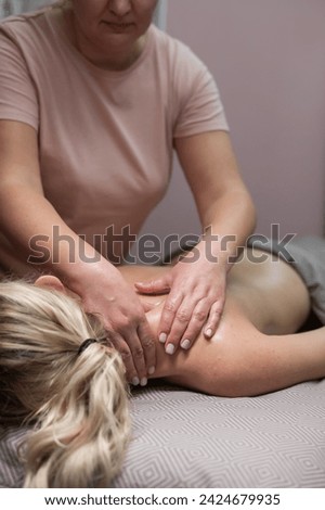 A woman undergoing a massage of the cervical-collar area. Vertical photo. 