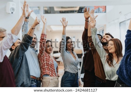 Business people with raised arms celebrating success at the office with smile and confidence on their faces.