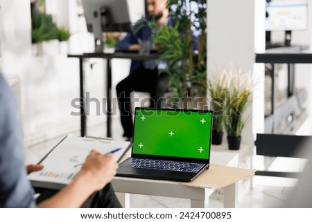 Financial analyst preparing for data analysis presentation using laptop with green screen in coworking space. Employee working at on portable computer with chroma key in business office
