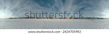 Reykjavik, Iceland - February 11, 2024: People relish a sunny, mild day on the frozen pond, with Reykjavik's City Hall and the Icelandic Parliament visible in the center.