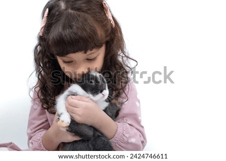 Little girl holds and kisses a cute rabbit on white background, easter concept 