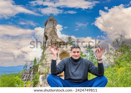 young handsome man on a rock on the Arakul shihan enjoys on a summer day Royalty-Free Stock Photo #2424749811