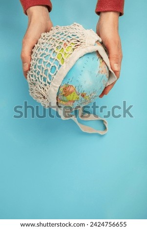 Hand holding globe on blue background. Environment protection. Top view, copy space