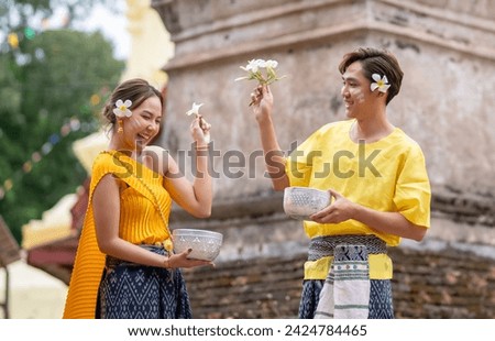A young boy and girl in Thai cultural clothing gather to splash in the Songkran Festival tradition Royalty-Free Stock Photo #2424784465