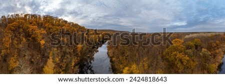Aerial panorama of autumn river with calm mirror water and cloudy sky. Wild colorful autumnal riverside nature in Ukraine