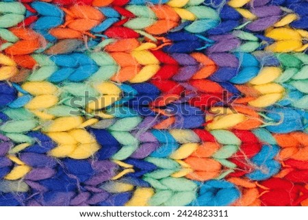 Close-up of a knitted colorful wool scarf, background texture of multicolored braided wool