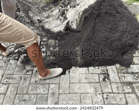Construction worker with a shovel moves the sand so that it is less compact and looser