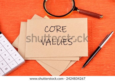 CORE VALUES word written on the envelope next to a magnifying glass, calculator, pen on an orange background Royalty-Free Stock Photo #2424834267