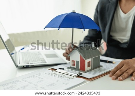 Holding hands holding an umbrella on the house Home insurance concept and family protection, safety, close-up photo