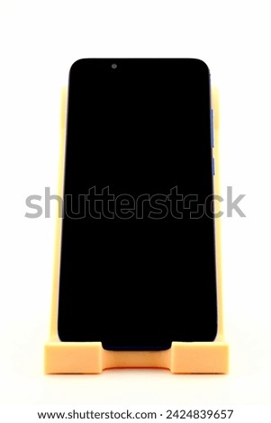 blue smartphone with blank screen on holder, side view, close-up on white background