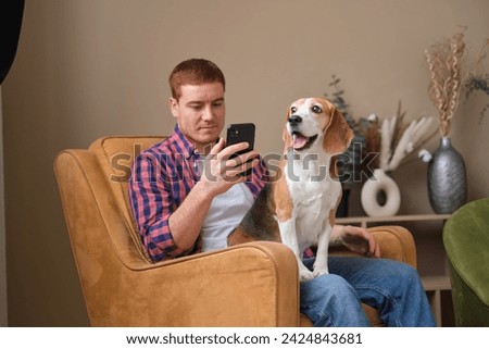 Engrossed in his phone, the man finds company with his loyal dog; their bond unshaken by the distractions of technology. Royalty-Free Stock Photo #2424843681