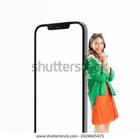 Cheerful beautiful Asian woman stand near big smartphone mockup of blank screen on white background, Full body of studio portrait. Royalty-Free Stock Photo #2424845425