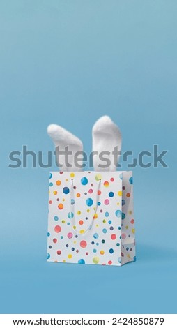 Easter sale, shopping, gift. Easter bunnys ears in a shopping bag, nice funny vertical photo . Blue background vertical composition poster