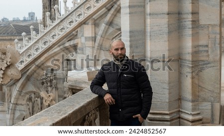 Milan marvel: A young tourist man smiles freely on the roof of Milan Cathedral, embracing the city's beauty with joy and charm.