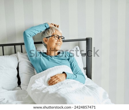 Portrait of a happy senior elderly woman relaxing in bed in the morning, a mature woman at home, bedding pillow and sheet