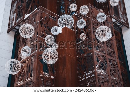 Metal structure with hanging light spheres in urban setting, creating visually appealing composition. Modern touch enhanced by glowing spheres, ideal for stock photography.