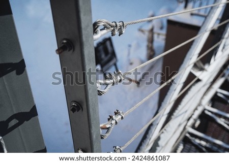 Closeup of stainless steel cables and fasteners on a metal railing, providing secure connection between railing and posts. Enhances safety as part of protective barrier.