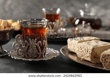 Turkish tea and sweets served in vintage tea set on black table, closeup