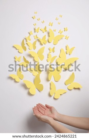 Woman with yellow paper butterflies on white background, top view