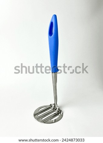 Cooking utensil tool or equipment. Mash potato masher or potato ricer with stainless steel material and blue handle. Object photography isolated on white studio background. Royalty-Free Stock Photo #2424873033