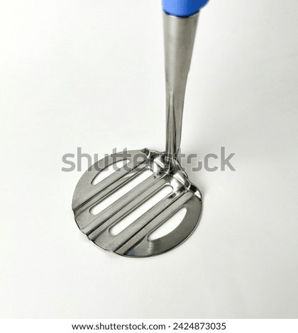 Cooking utensil tool or equipment. Mash potato masher or potato ricer with stainless steel material and blue handle. Object photography isolated on white studio background. Royalty-Free Stock Photo #2424873035