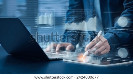Businessman uses computer with pen. Financial graph analysis concepts Stock market information. Reporting and Statistics Including KPI analysis on a blue background. Royalty-Free Stock Photo #2424880677