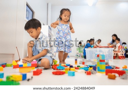 Adorable preschool asian kid boy and girl enjoying play colorful building toy block indoor education Royalty-Free Stock Photo #2424884049