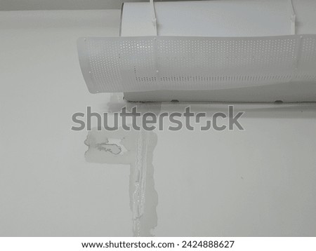 Air conditioner with air deflector, shown the wet wall because the AC has a leak from the condensate drain pipe. Royalty-Free Stock Photo #2424888627