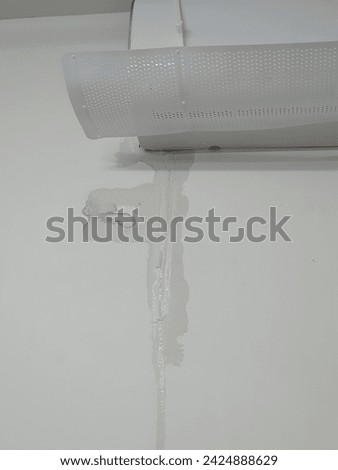 Air conditioner with air deflector, shown the wet wall because the AC has a leak from the condensate drain pipe. Royalty-Free Stock Photo #2424888629