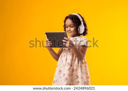 Portrait of smiling kid girl with headphones using tablet. Lifestyle, leasure and gadget addiction concept